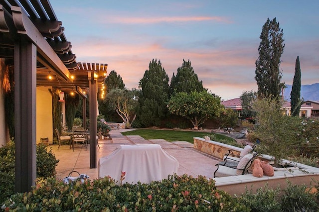 patio terrace at dusk with area for grilling and a pergola