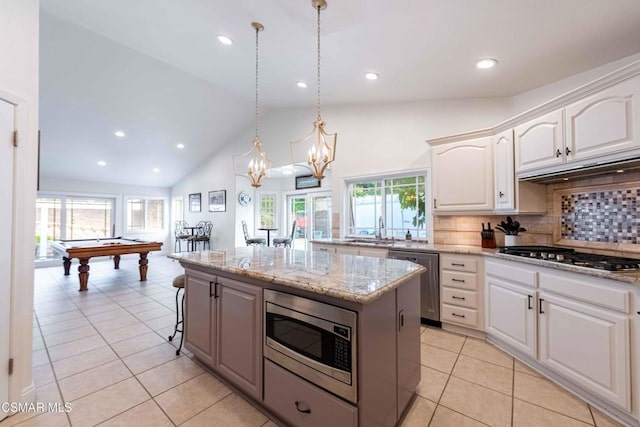 kitchen with pendant lighting, white cabinetry, a center island, light stone counters, and stainless steel appliances