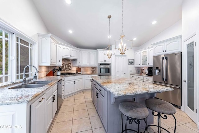 kitchen with appliances with stainless steel finishes, a center island, white cabinets, and light stone counters