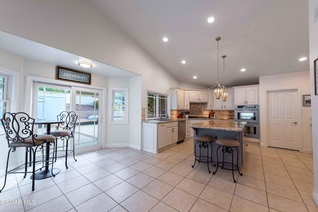 kitchen featuring a breakfast bar, a center island, stainless steel appliances, light stone countertops, and white cabinets