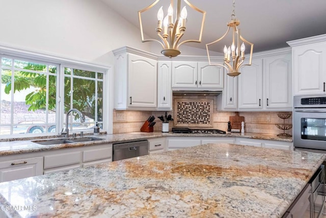 kitchen with appliances with stainless steel finishes, sink, white cabinets, hanging light fixtures, and an inviting chandelier