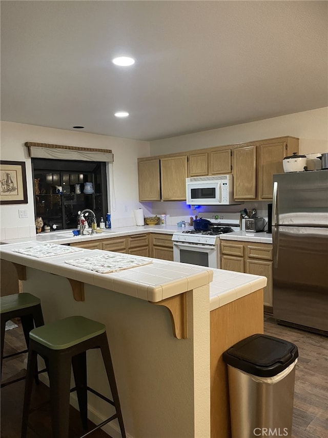 kitchen with sink, white appliances, tile counters, and a breakfast bar