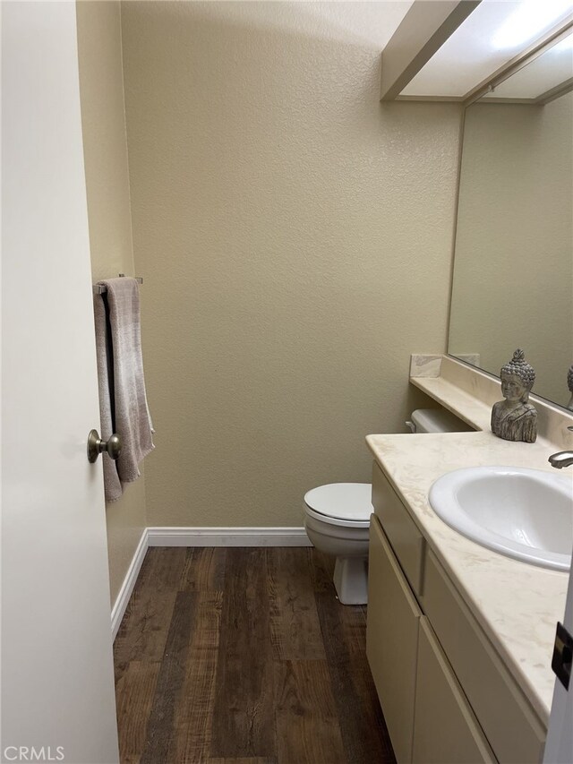 bathroom featuring vanity, wood-type flooring, and toilet