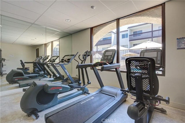 exercise room featuring a paneled ceiling and plenty of natural light