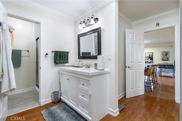 bathroom with hardwood / wood-style flooring, vanity, crown molding, and walk in shower