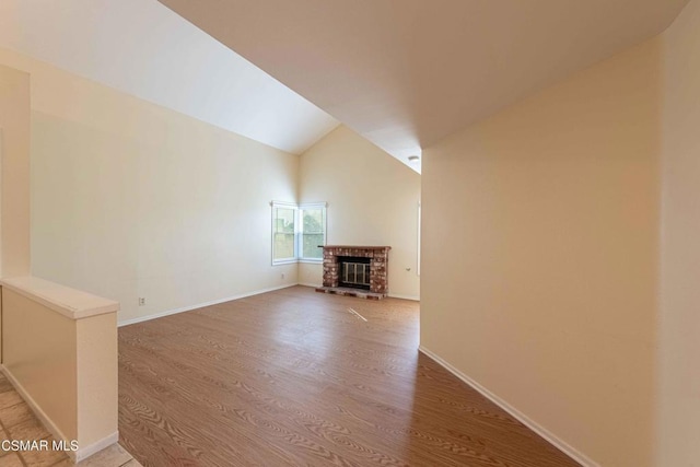 unfurnished living room with vaulted ceiling, hardwood / wood-style floors, and a fireplace