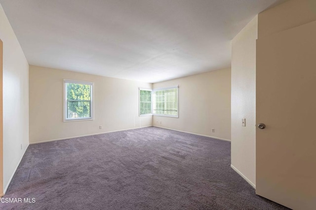 spare room featuring dark colored carpet