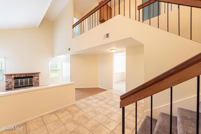 stairway with a towering ceiling and a brick fireplace