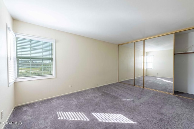 unfurnished bedroom with dark carpet and a closet