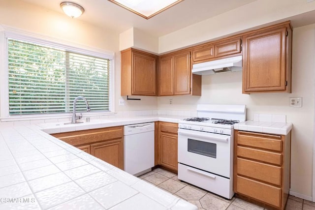 kitchen with light tile patterned flooring, white appliances, tile counters, and sink