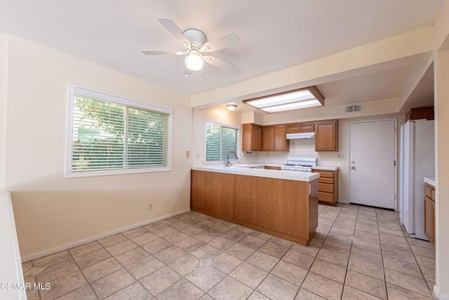 kitchen with ceiling fan, white appliances, kitchen peninsula, and light tile patterned floors