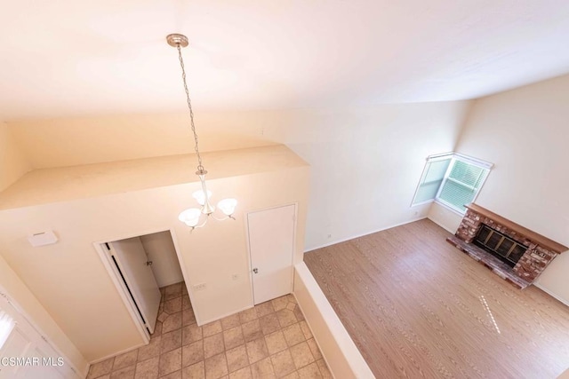 unfurnished living room featuring vaulted ceiling, a brick fireplace, and a notable chandelier