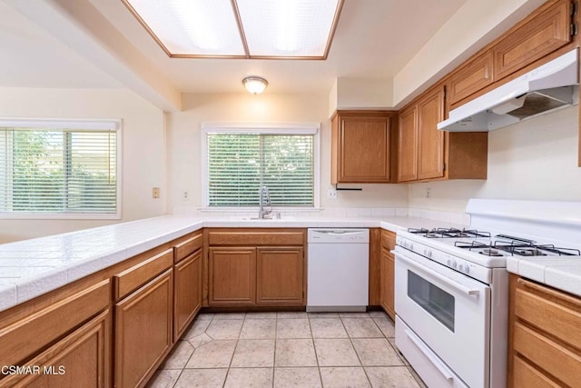 kitchen featuring white appliances, tile counters, and a wealth of natural light