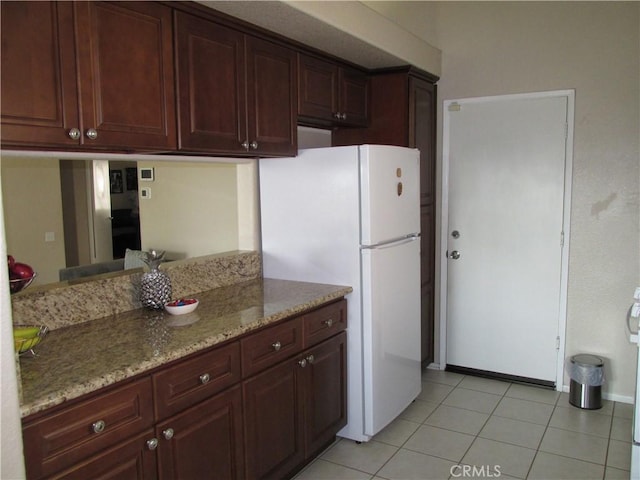 kitchen with light stone countertops, light tile patterned flooring, and white fridge