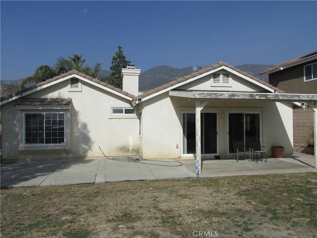 back of property featuring a mountain view, a yard, and a patio