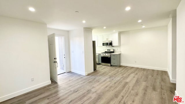 kitchen with light hardwood / wood-style flooring, stainless steel appliances, and white cabinets