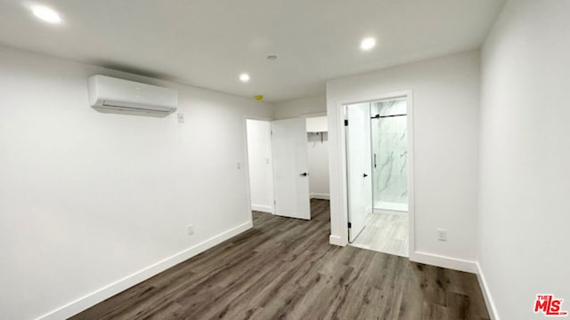 unfurnished room featuring dark wood-type flooring and a wall unit AC