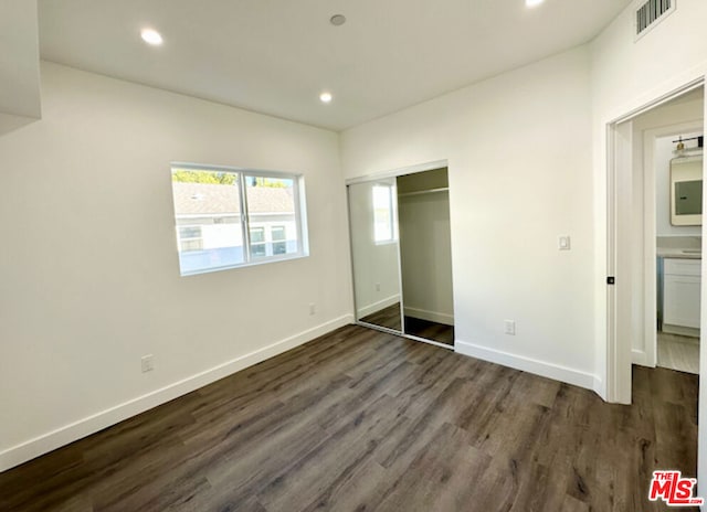 unfurnished bedroom with dark hardwood / wood-style floors and a closet