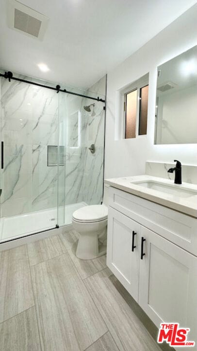 bathroom featuring walk in shower, vanity, and toilet