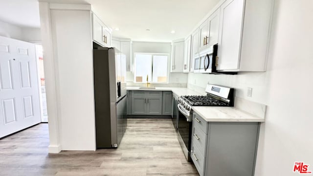 kitchen featuring sink, gray cabinets, stainless steel appliances, and light hardwood / wood-style floors