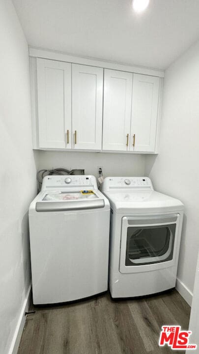 clothes washing area with cabinets, dark hardwood / wood-style floors, and washer and clothes dryer