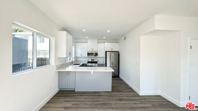 kitchen featuring white cabinetry, sink, a breakfast bar area, kitchen peninsula, and stainless steel appliances