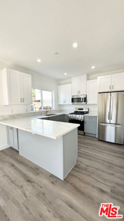 kitchen featuring white cabinetry, light hardwood / wood-style floors, stainless steel appliances, and kitchen peninsula