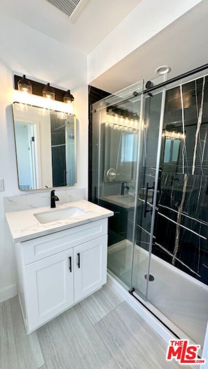 bathroom featuring vanity and a shower with shower door