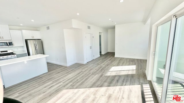 kitchen with stainless steel appliances, white cabinetry, and light hardwood / wood-style flooring