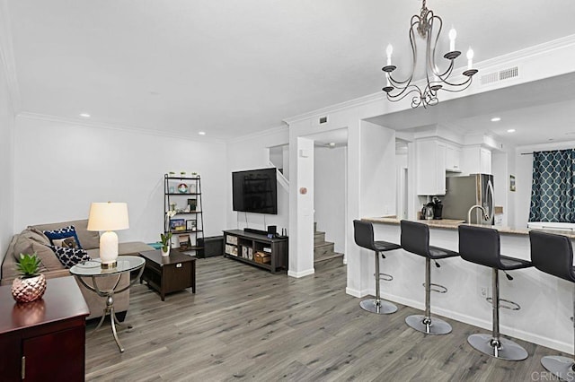 interior space featuring white cabinetry, decorative light fixtures, stainless steel refrigerator, kitchen peninsula, and hardwood / wood-style floors