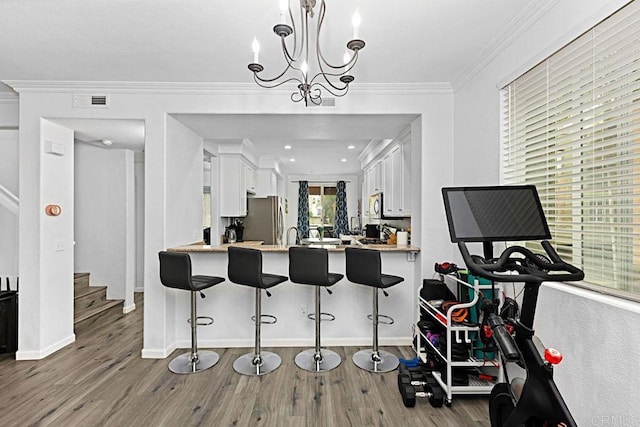 kitchen with appliances with stainless steel finishes, a kitchen bar, kitchen peninsula, and white cabinets