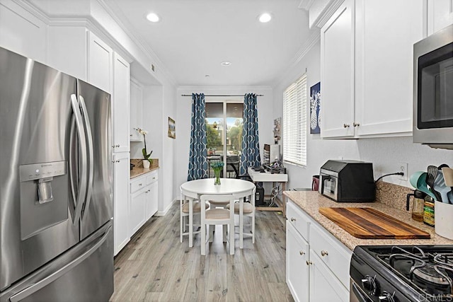 kitchen with light hardwood / wood-style flooring, appliances with stainless steel finishes, white cabinetry, light stone counters, and ornamental molding