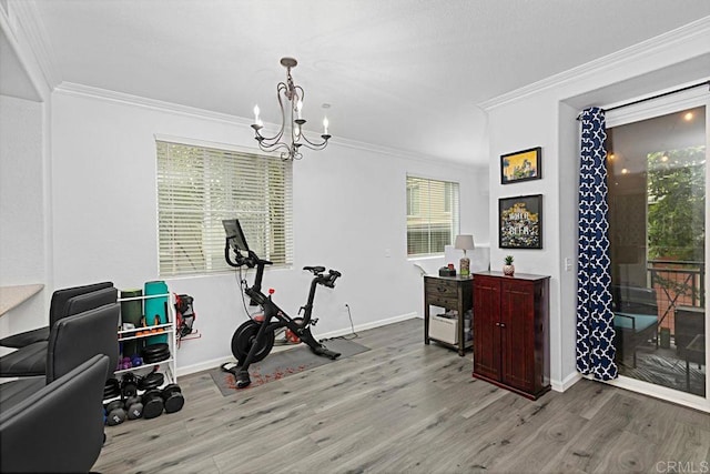 exercise room with ornamental molding, an inviting chandelier, and light hardwood / wood-style floors