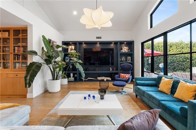 living room with high vaulted ceiling and light wood-type flooring