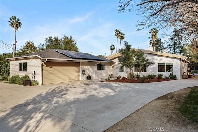 single story home with a garage and solar panels