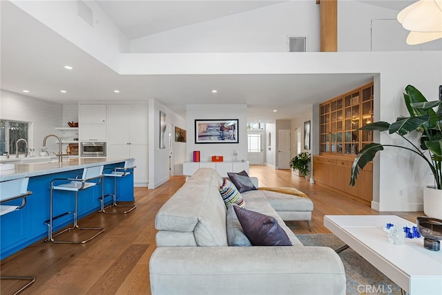 living room with high vaulted ceiling and light hardwood / wood-style floors