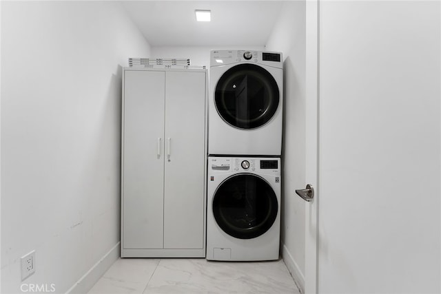 clothes washing area featuring stacked washer and dryer and cabinets