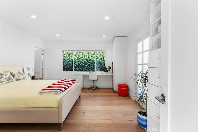 bedroom featuring multiple windows, built in desk, and light hardwood / wood-style floors