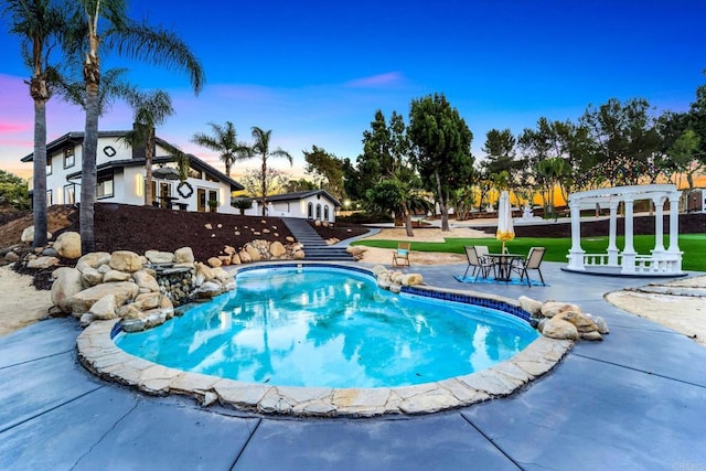 pool at dusk featuring a pergola