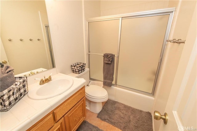 full bathroom with tile patterned flooring, enclosed tub / shower combo, vanity, and toilet