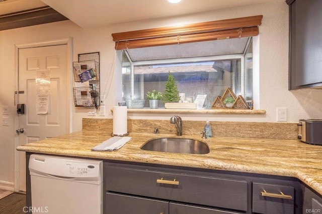 kitchen with dishwasher, light stone countertops, and sink