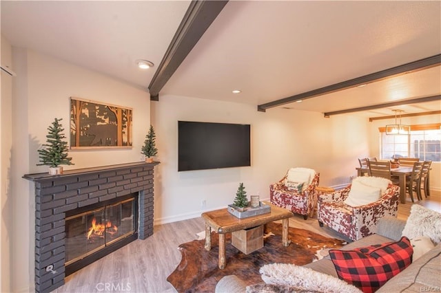 living room featuring light wood-type flooring, a fireplace, and beam ceiling