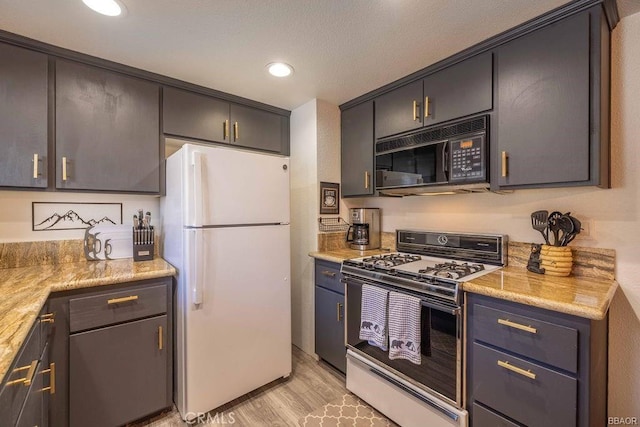 kitchen with white appliances, light stone countertops, and light hardwood / wood-style flooring