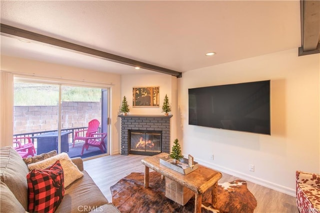 living room with beamed ceiling, hardwood / wood-style floors, and a brick fireplace