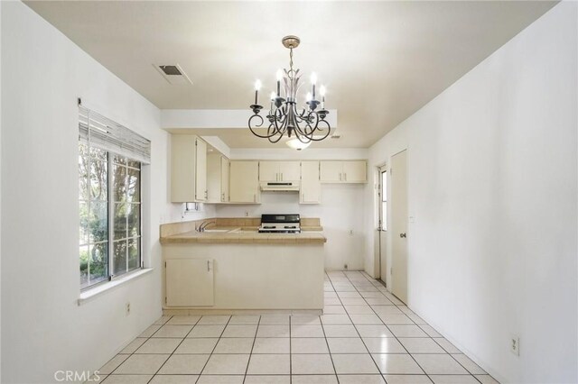 kitchen with light tile patterned floors, under cabinet range hood, a peninsula, stove, and visible vents