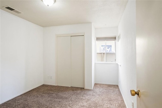 unfurnished bedroom with carpet floors, baseboards, visible vents, and a closet