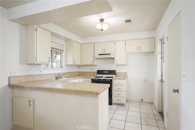 kitchen featuring light tile patterned flooring, under cabinet range hood, a peninsula, a sink, and gas range oven