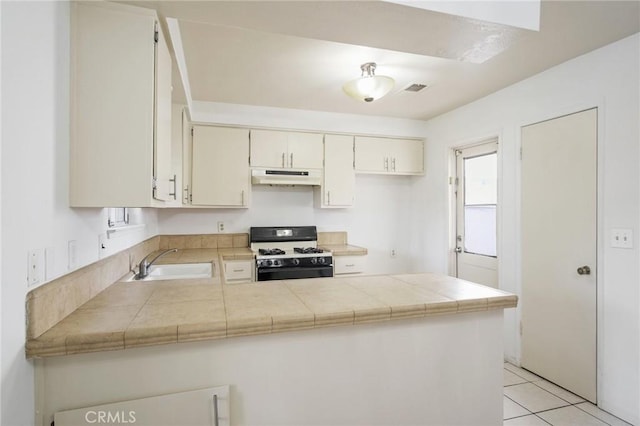 kitchen featuring under cabinet range hood, a peninsula, a sink, visible vents, and range with gas stovetop