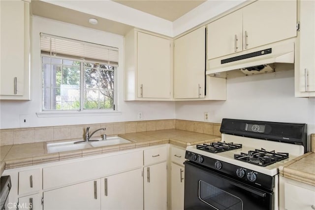 kitchen featuring under cabinet range hood, a sink, and range with gas cooktop