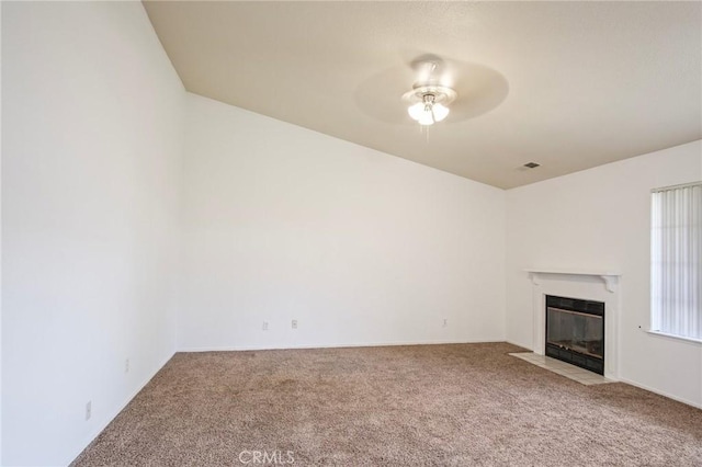 unfurnished living room featuring a fireplace with flush hearth, visible vents, ceiling fan, and carpet flooring